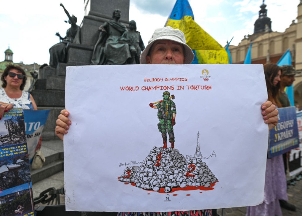 A protester in Krakow holds a powerful poster related to the Summer Olympics in Paris and the words “World Champions In Torture,” outside Krakow’s Adam Mickiewicz monument, on July 23, 2023, in Krakow, Poland. (Source: Getty Images) A protester in Krakow holds a powerful poster related to the Summer Olympics in Paris and the words “World Champions In Torture,” outside Krakow’s Adam Mickiewicz monument, on July 23, 2023, in Krakow, Poland. (Source: Getty Images)