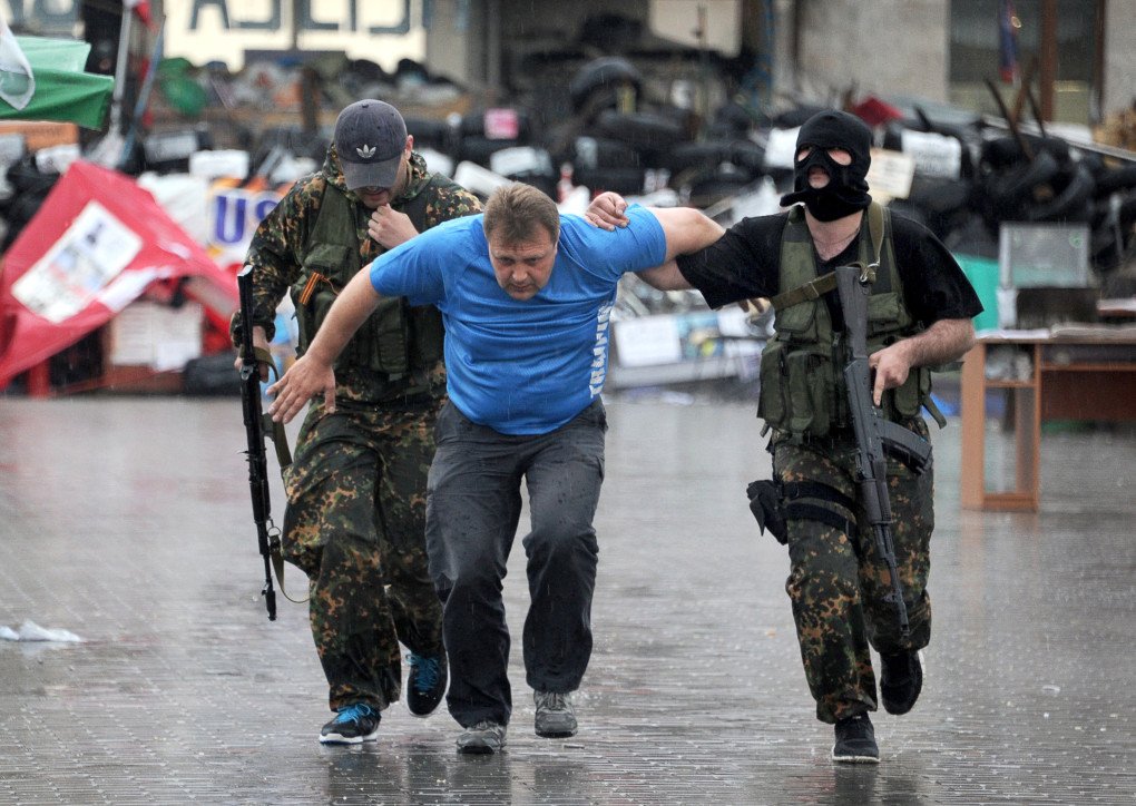 Members of the Vostok (east) battalion, a pro-Russia militia, escort an activists of so-called self proclaimed People's Republic of Donetsk after detaining several of them following their storming of the regional state building in the eastern Ukrainian city of Donetsk on May 29, 2014. Photo by VIKTOR DRACHEV/AFP via Getty Images