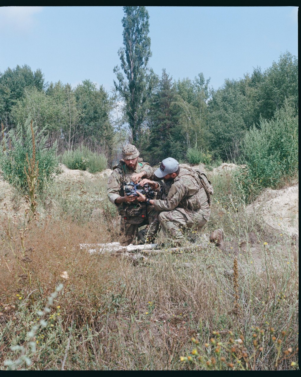 Groot and Xerox kneel as they fix explosives to the Mavic drone they are training with that day, in anticipation for their upcoming mission. Ukraine, August 2025. Photo by Lucile Brizard/UNITED24 Media.