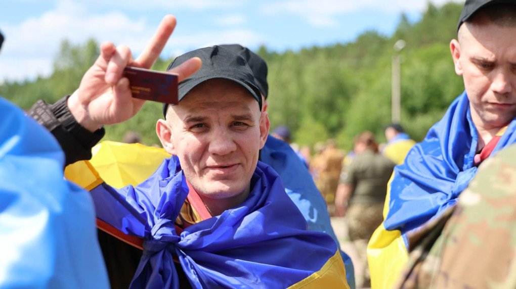 Ukrainian soldiers with national flags draped over their shoulders after returning home in Ukraine, on June 26, 2026. (Source: Coordination Headquarters for the Treatment of Prisoners of War)