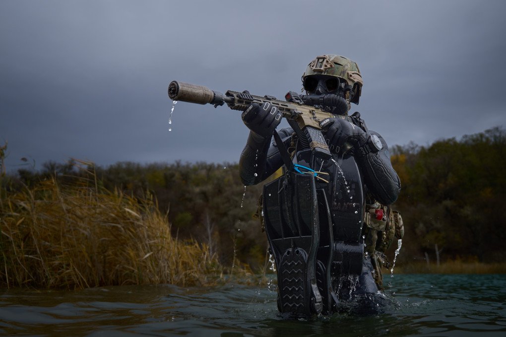 A combat diver exits the water onto the shore. All equipment required for underwater movement (fins, etc.) is removed underwater and secured to his load-bearing system. Photo: Mykyta Shandyba/UNITED24 Media.