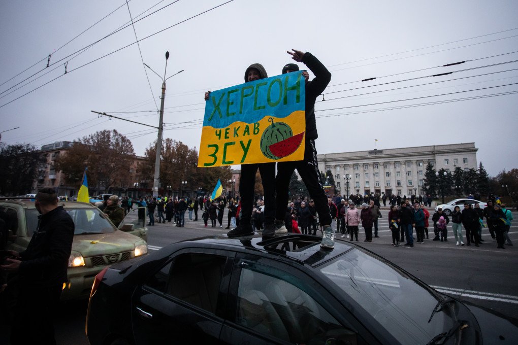 Two men stand on atop a car with a poster "Kherson was waiting for the Armed Forces of Ukraine" during the celebration of the city's liberation on November 12, 2022 in Kherson, Ukraine. Kherson, which had been under Russian occupation since March, was liberated on November 11 as result of a counteroffensive by Ukrainian forces in the south. (Photo by Yevhenii Zavhorodnii/Global Images Ukraine via Getty Images) kherson region liberation