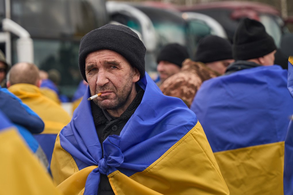 A freed defender, wrapped in a Ukrainian flag, smokes a cigarette during the exchange, March 6, 2026, undisclosed location, Ukraine. Photo by Mykyta Shandyba, UNITED24 Media