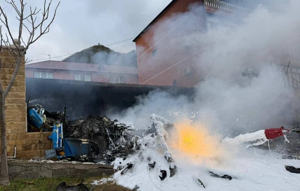 Burnt wreckage of the Ka-226 helicopter lies at the crash site near a damaged residential building in Achi-Su, Dagestan. (Source: Getty Images)