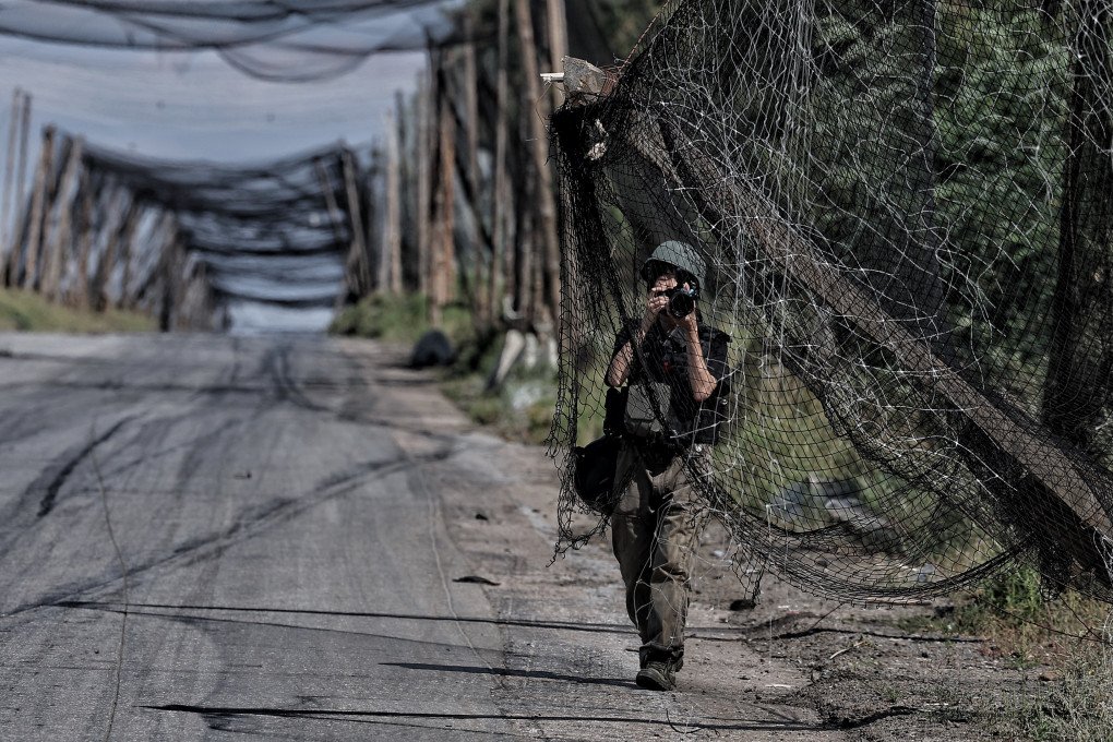A photographer wearing protective gear photographs an anti-drone net installed over a road on September 4, 2026 in Druzhkivka, Donetsk region, Ukraine (source: Yan Dobronosov/Global Images Ukraine via Getty Images)