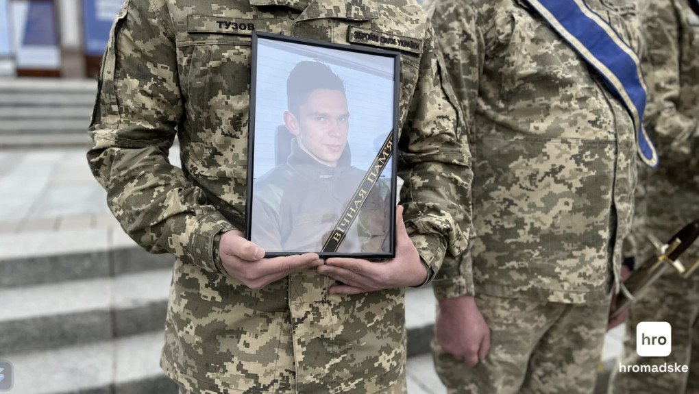 A Ukrainian soldier holds a framed photo of Lithuanian volunteer Tomas Valentelis during the ceremony. (Source: hromadske)
