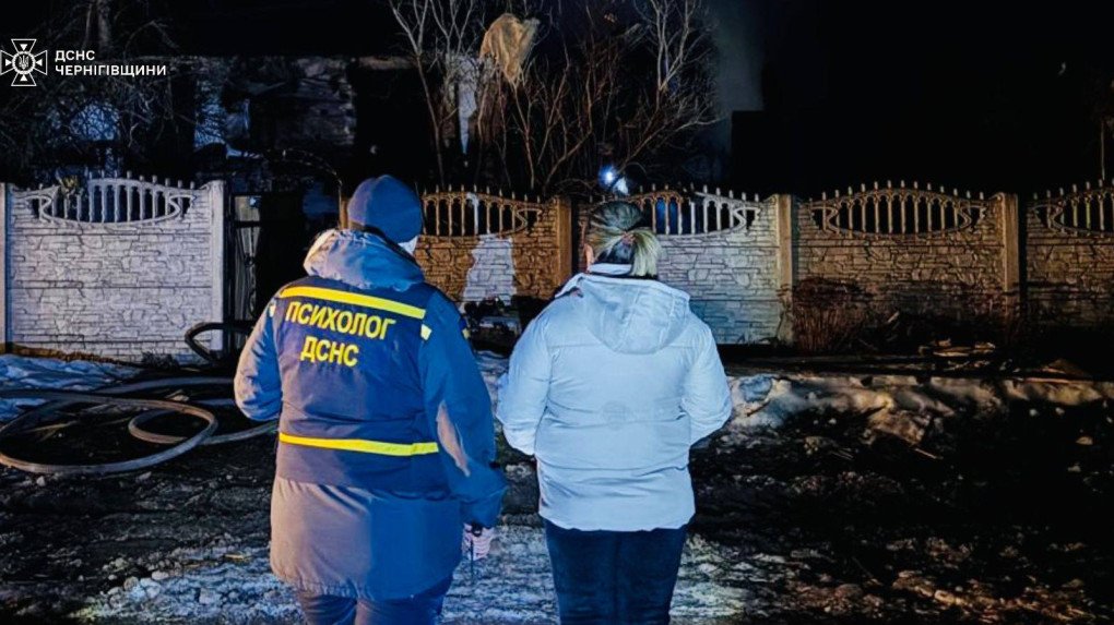 Psicólogo del Servicio Estatal de Emergencias de Ucrania acompaña a una mujer frente a una vivienda destruida tras el impacto de un dron ruso en la región de Cherníhiv.