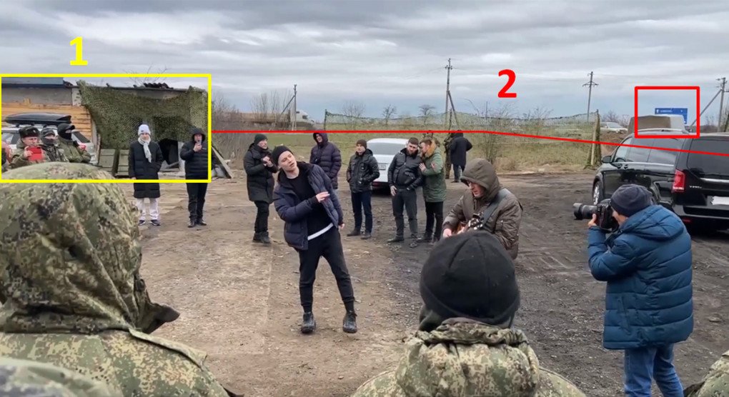 SHAMAN realiza una actuación mientras los analistas destacan dos pistas clave de geolocalización: un edificio camuflado (izquierda) y una señal de tráfico azul (derecha) captados al fondo. (Fuente: Molfar)