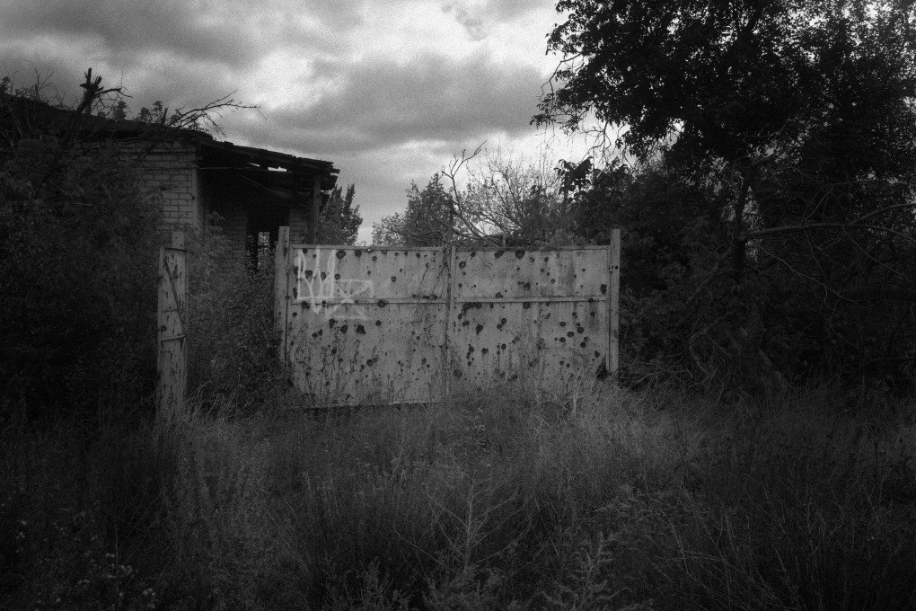 Ukrainian Trident on a bullet-ridden fence. Dovhenke, Ukraine. October, 2025. Photo by Joshua Olley/UNITED24 Media.