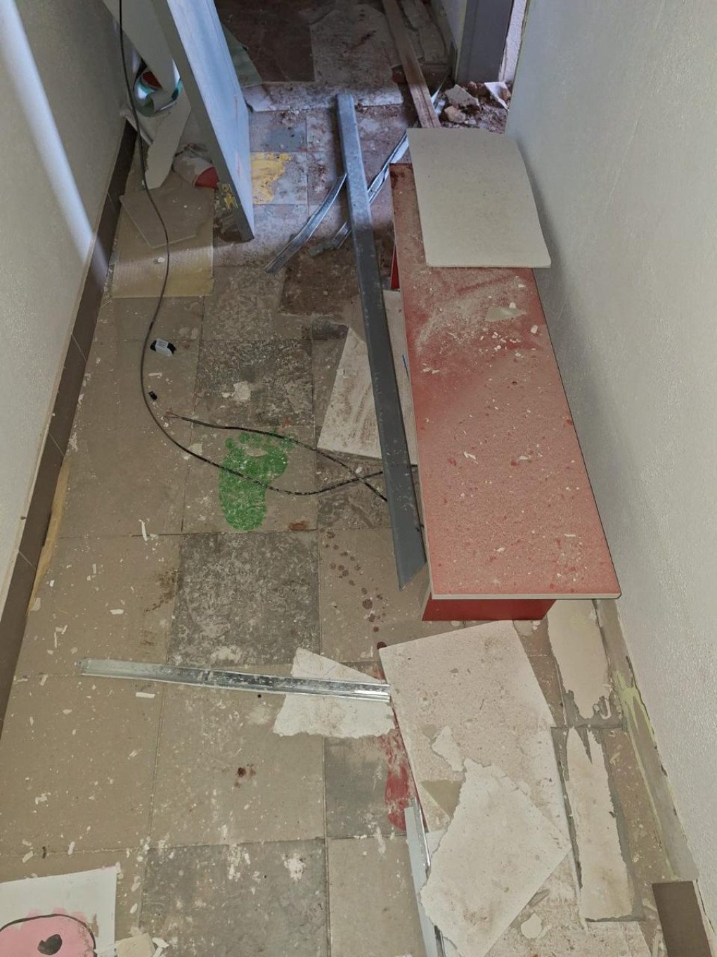 A narrow passage inside the building is littered with shattered tiles and broken furniture after the Russian strike. (Source: SBU)