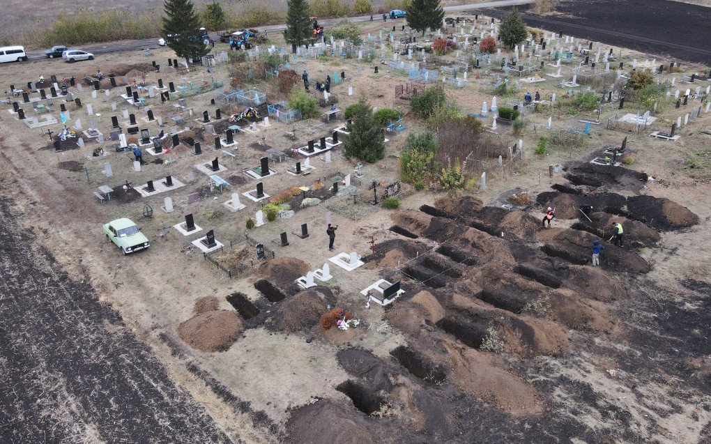 An aerial photograph taken with a drone shows workers digging graves for the victims of an airstrike earlier in the month, at the cemetery in the Groza village, Kharkiv region, on October 9, 2023, amid the Russian invasion of Ukraine. (Photo by GENYA SAVILOV/AFP via Getty Images)