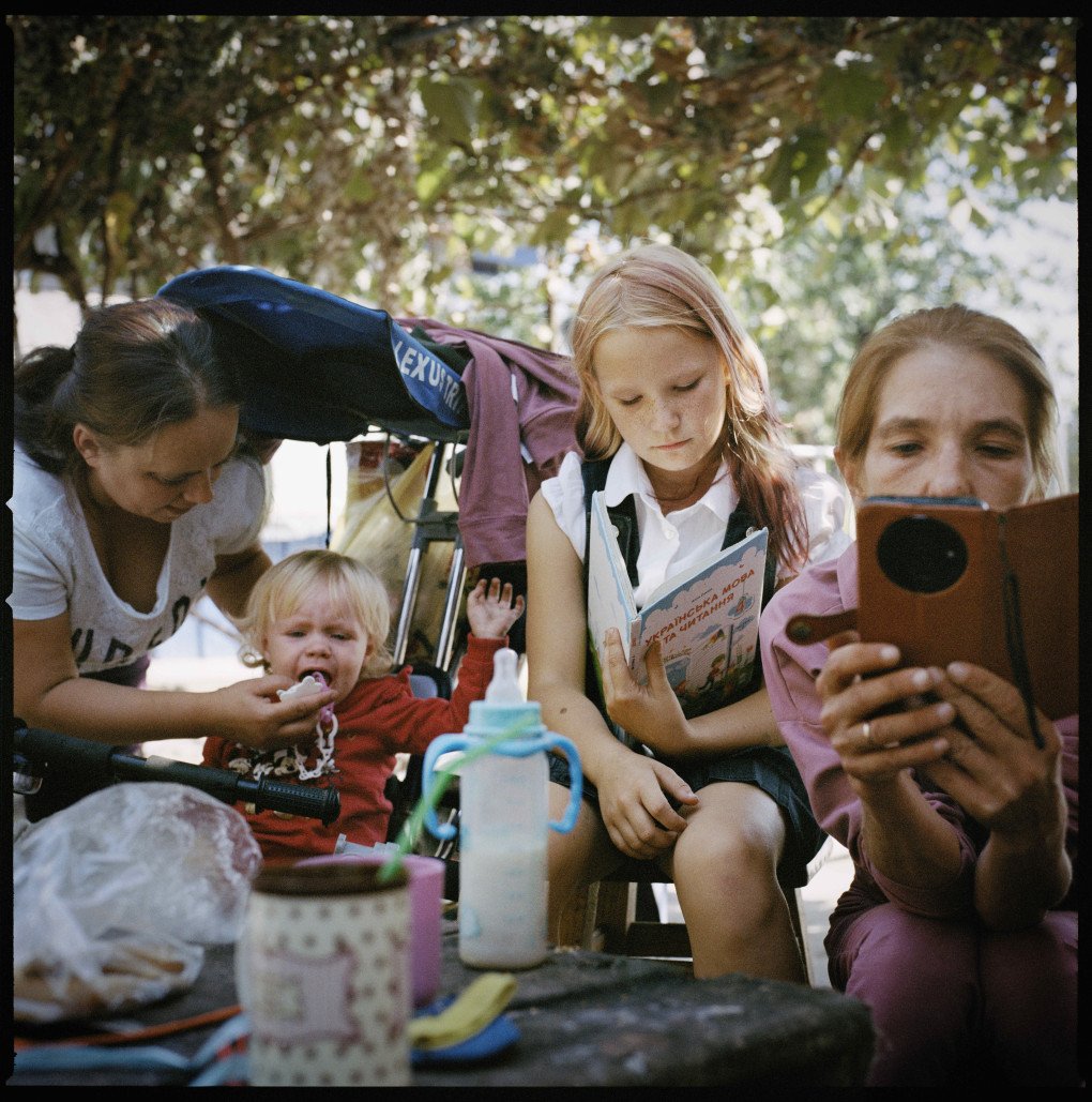 Olha Hrynyk (right) with her daughter Myroslava (centre) and neighbours, in the Poltava region, where they moved after being displaced from Avdiivka, 2024.From the series 5K from the Frontline. (Image: Anastasia Taylor-Lind) Olha Hrynyk (right) with her daughter Myroslava (centre) and neighbours, in the Poltava region, where they moved after being displaced from Avdiivka, 2024.From the series 5K from the Frontline. (Image: Anastasia Taylor-Lind)