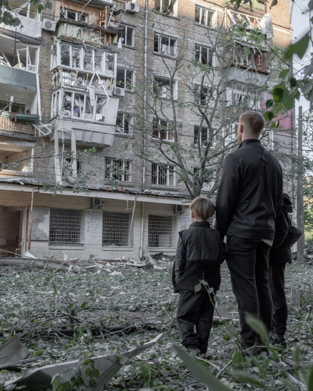 Un adulto y un niño observan un bloque de viviendas dañado en Kyiv, donde la noche de ataques rusos dejó ventanas arrancadas, pisos abiertos y hogares destruidos. (Foto: Nikita Lysovyi) Adulto y niño observan un edificio de viviendas dañado en Kyiv tras el ataque ruso con misiles y drones.