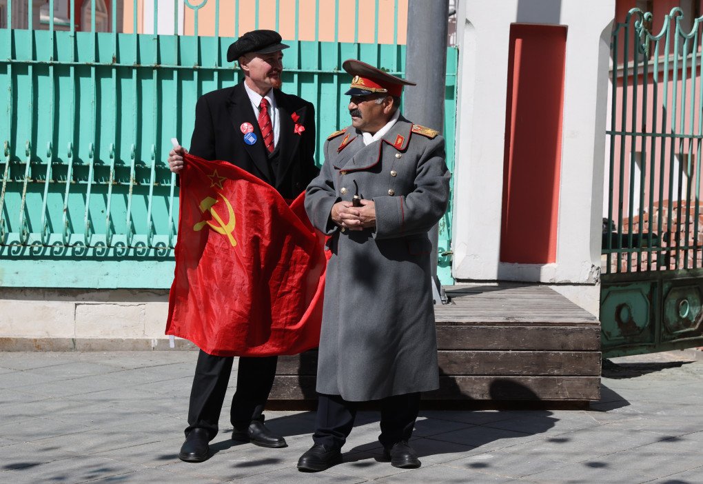Men, wearing costumes of Soviet leaders Vladimir Lenin and Joseph Stalin, holding Soviet flag, pose for a photograph, near the Kremlin, at Red Square, on April 24, 2024 in Moscow, Russia. Photo by Contributor/Getty Images.
