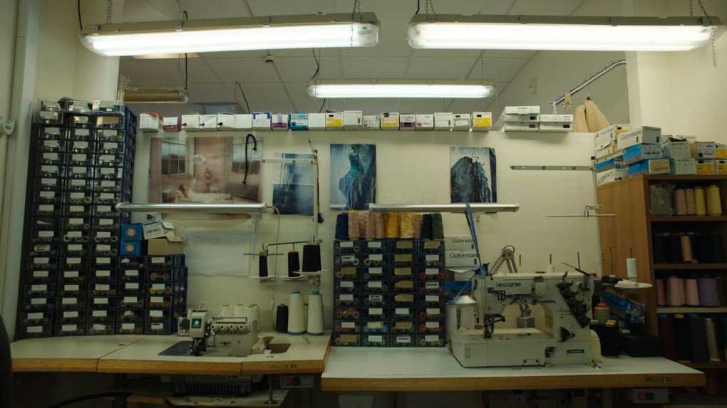 A workspace with threads, sewing machines, and photographs. (Source: press office)