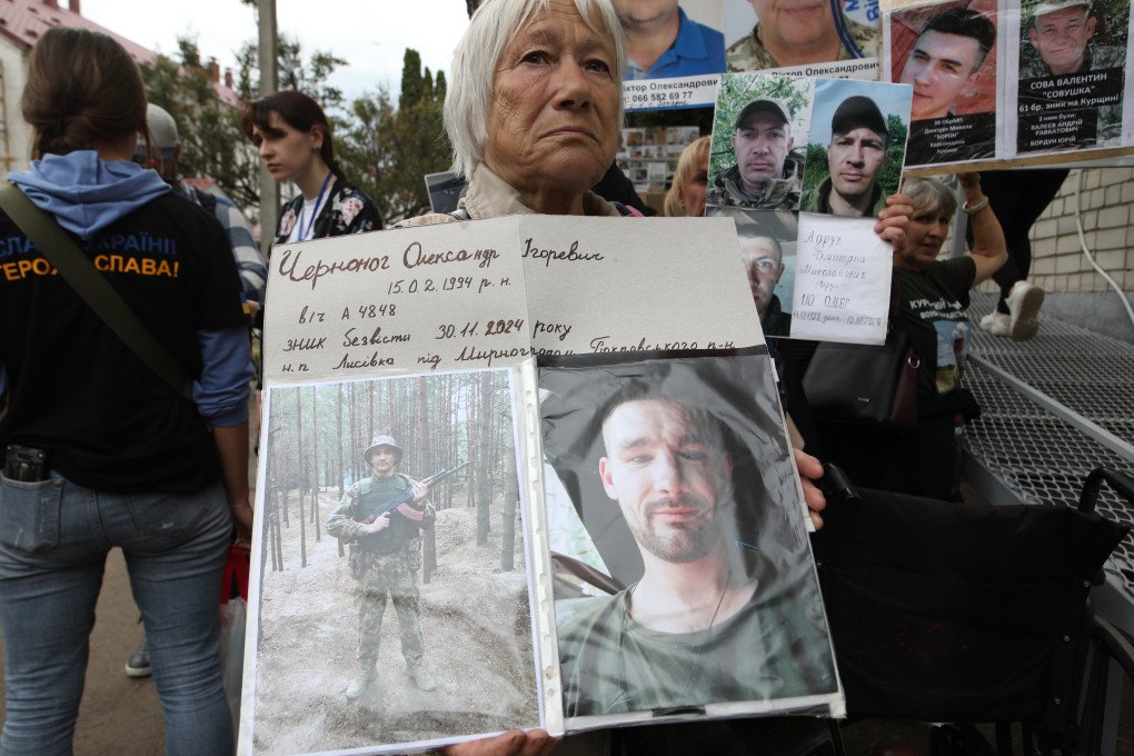 A woman holds photos of missing soldier Oleksandr, hoping one of the returning soldiers might recognize him. Photo: Josh Olley for UNITED24 Media