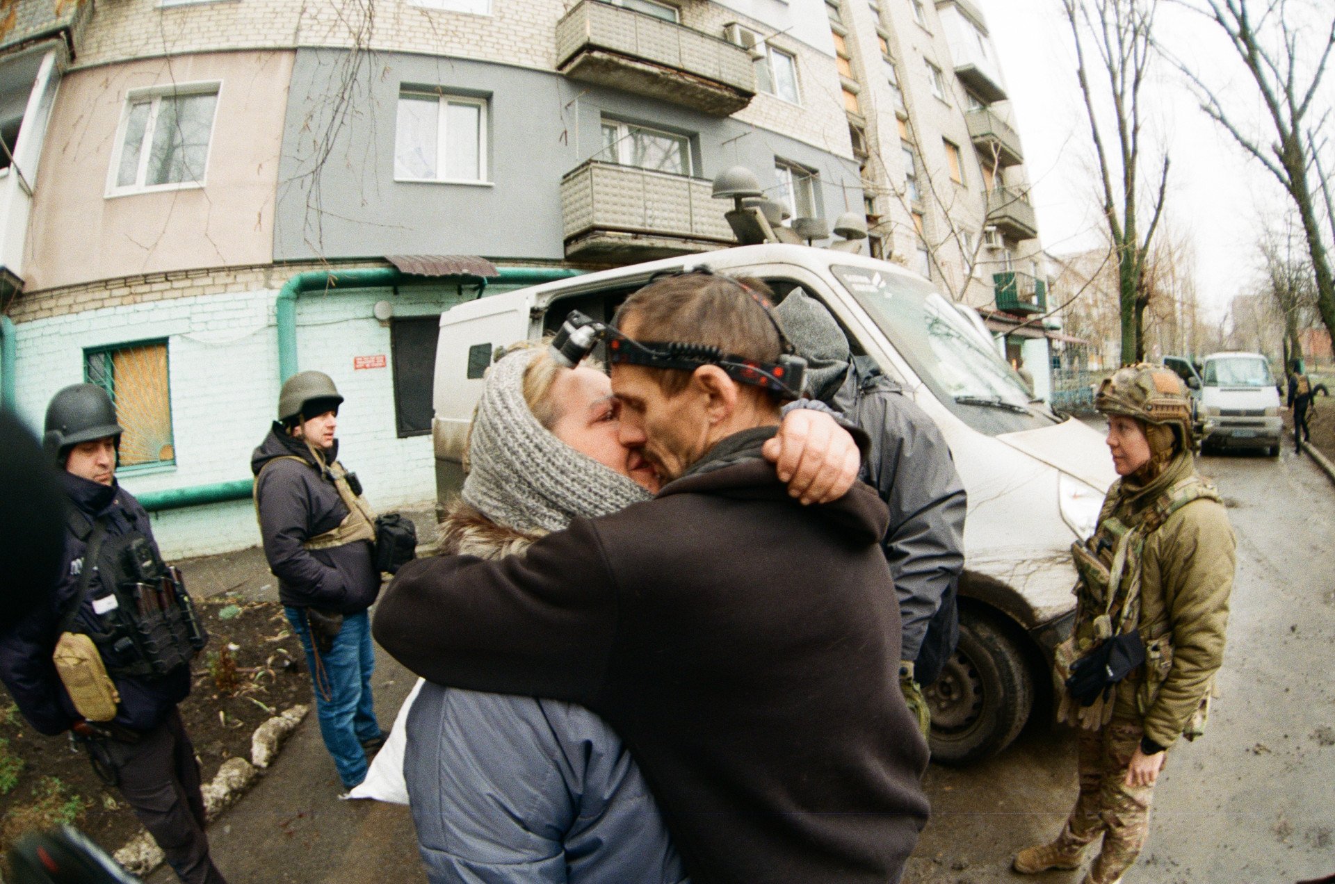 MAR 02 — Natalia shares a final embrace with her husband before leaving their hometown of Pokrovsk. She and her 16-year-old son are being evacuated by the “White Angels” special police unit, while her husband stays behind to care for her ailing mother in their basement. The White Angels are expected to return for him in a week. (Photo by Anton Shtuka)