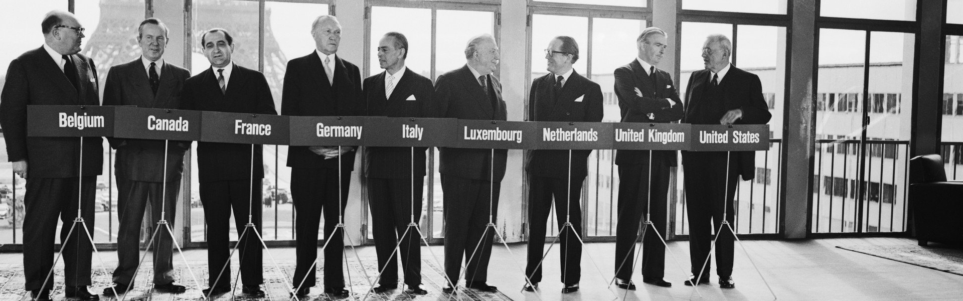 Foreign ministers of nine Western countries meet in Paris to expand the 1948 Brussels Treaty—a collective defense agreement signed by Belgium, France, Luxembourg, the Netherlands, and the UK to ensure mutual assistance in case of attack, especially amid post-WWII Soviet threats—paving the way for NATO enlargement and establishing controls for rearming West Germany, with representatives from Belgium, Canada, France, Germany, Italy, Luxembourg, the Netherlands, the UK, and the US. (Source: Getty Images) Foreign ministers of nine Western countries meet in Paris to expand the 1948 Brussels Treaty—a collective defense agreement signed by Belgium, France, Luxembourg, the Netherlands, and the UK to ensure mutual assistance in case of attack, especially amid post-WWII Soviet threats—paving the way for NATO enlargement and establishing controls for rearming West Germany, with representatives from Belgium, Canada, France, Germany, Italy, Luxembourg, the Netherlands, the UK, and the US. (Source: Getty Images)