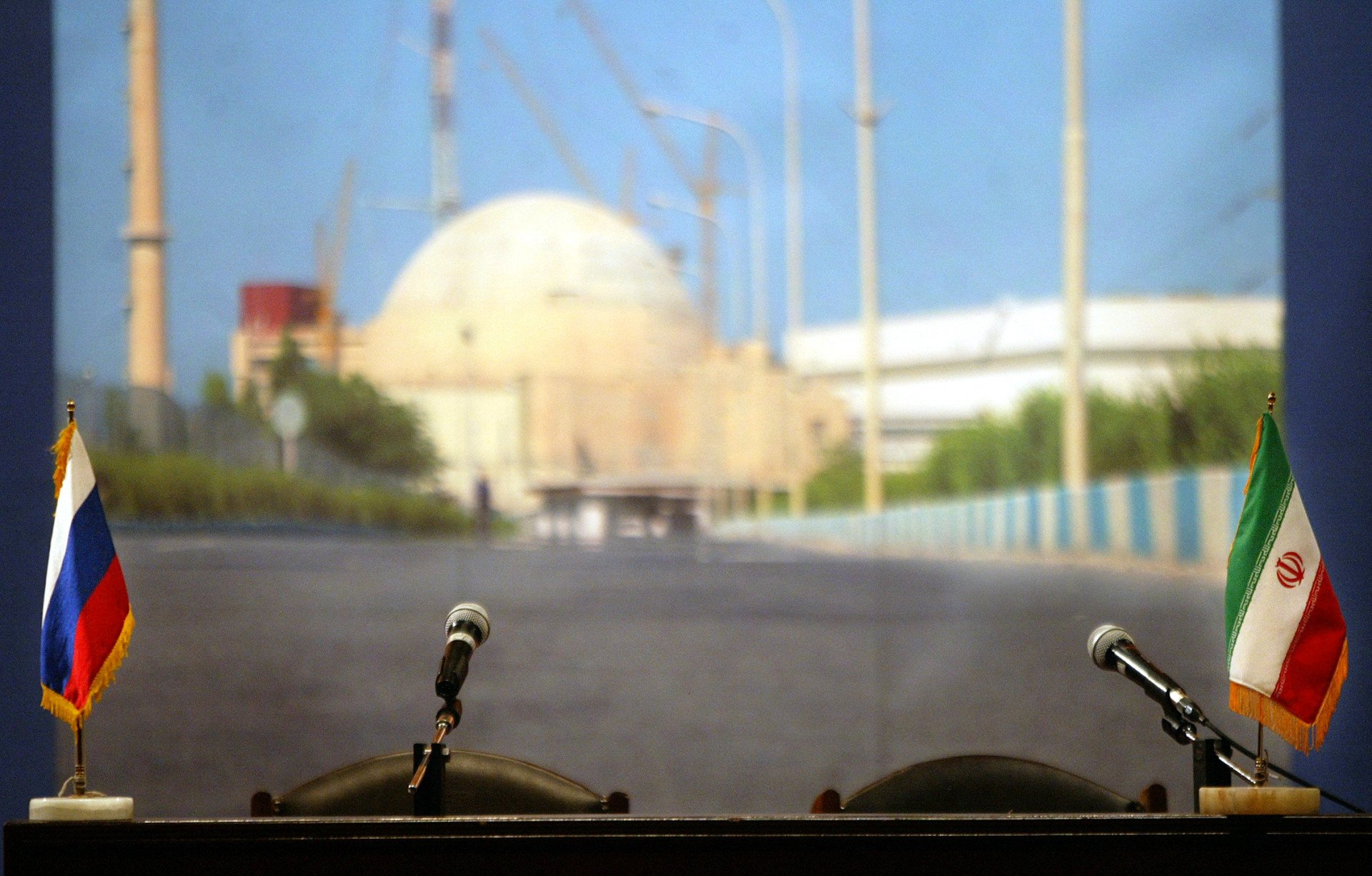 Russian and Iranian flags infront of a photograph of the Iranian nuclear facility