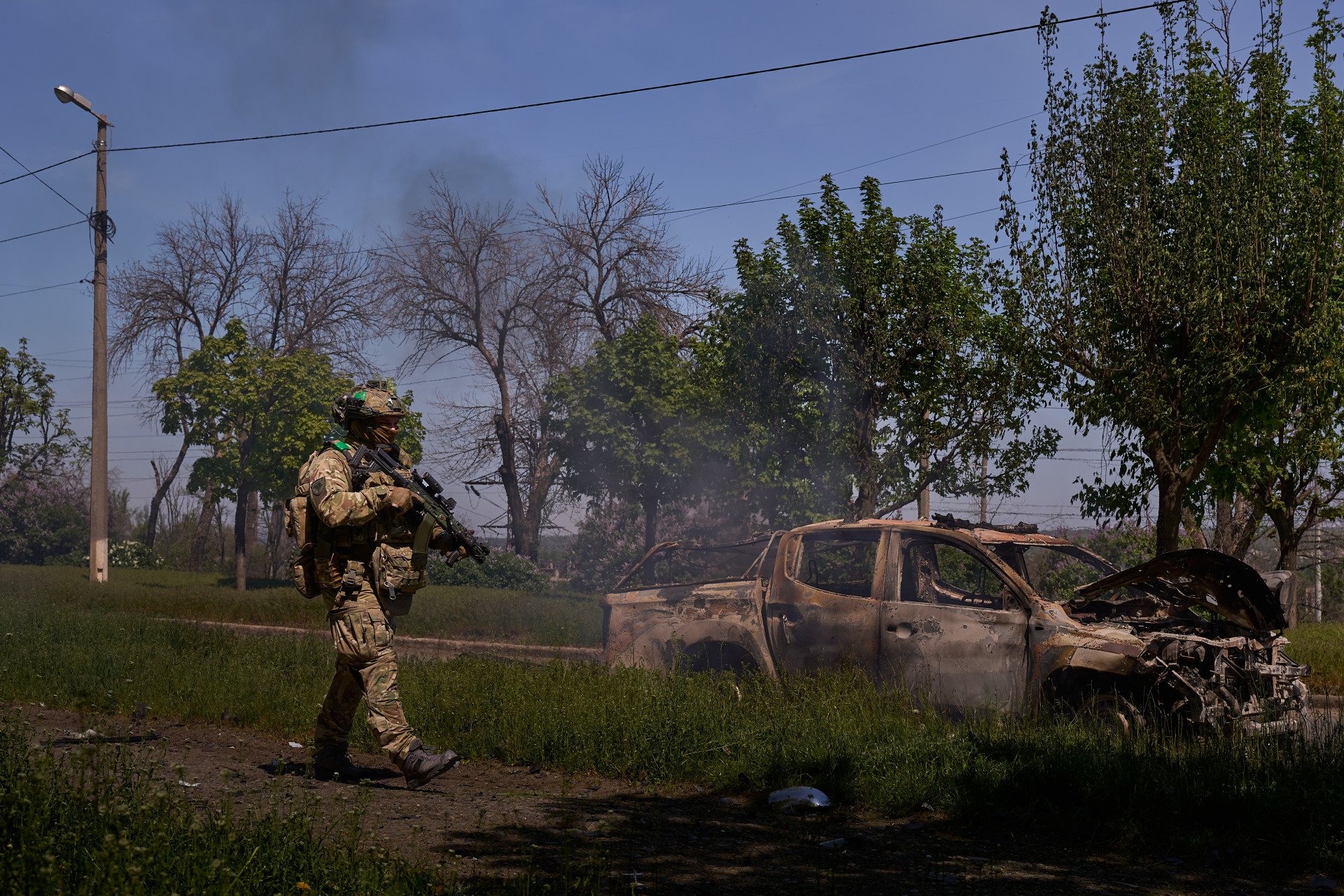 A Ukrainian soldier stands beside a car burned out after an attack by the Russian army. (Photo: Mykyta Shandyba/ UNITED24 Media)
