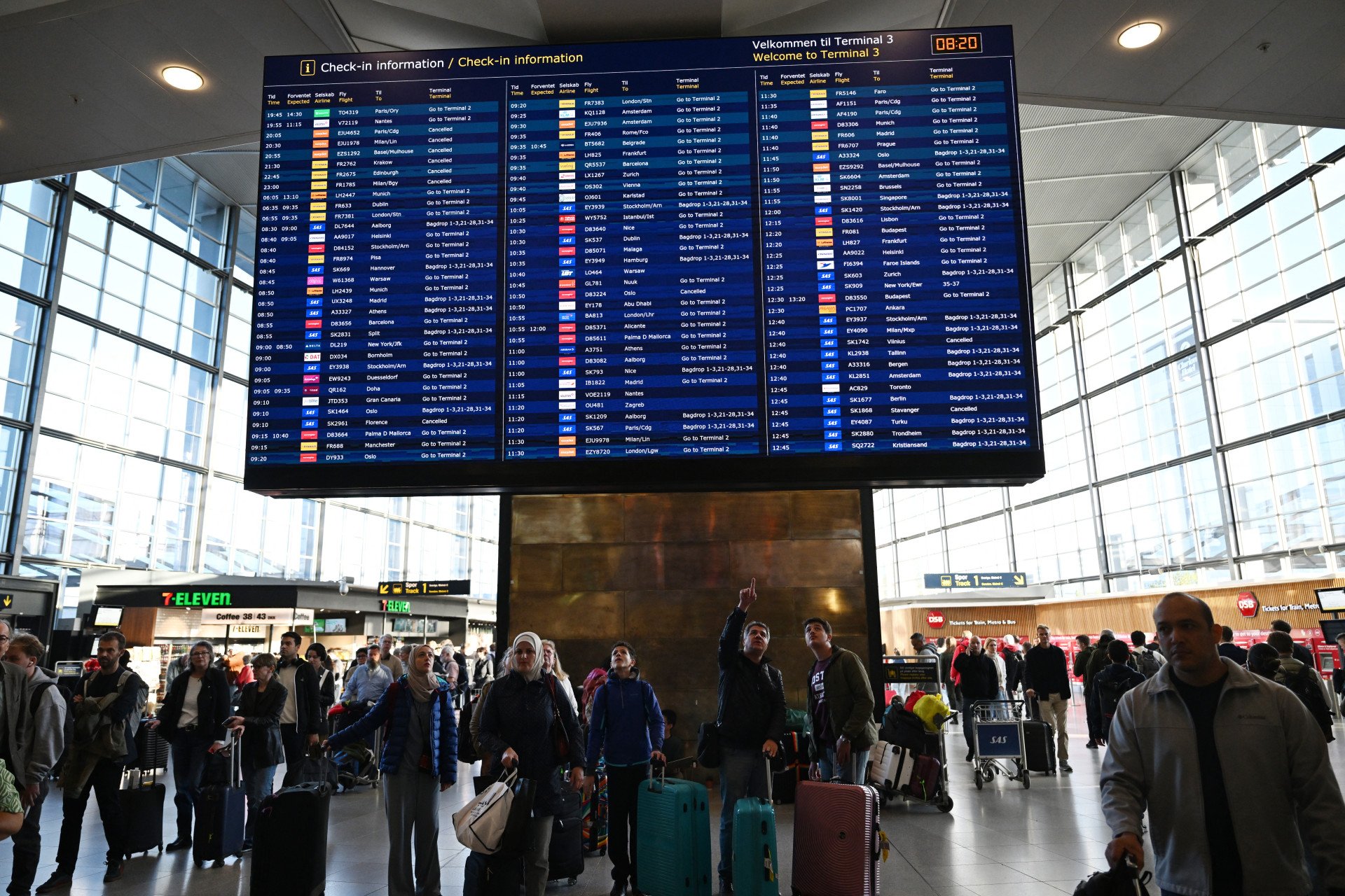 Los pasajeros consultan un panel con información sobre los vuelos en el aeropuerto de Copenhague, Dinamarca, el 23 de septiembre de 2025. Los aeropuertos de Copenhague y Oslo reabrieron el martes 23 de septiembre, horas después de que unos drones no identificados en su espacio aéreo provocaran el desvío o la cancelación de decenas de vuelos, lo que afectó a miles de pasajeros. Foto de Sergei Gapon/AFP vía Getty Images.