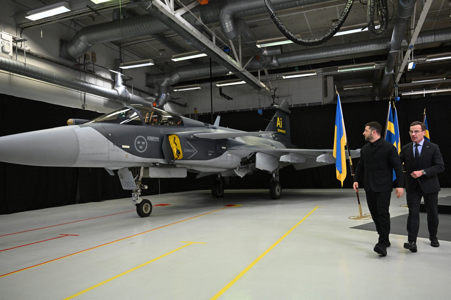El primer ministro sueco, Ulf Kristersson (derecha), y el presidente ucraniano, Volodymyr Zelenskyy, pasan junto a un caza Gripen después de ofrecer una conferencia de prensa conjunta en Linköping, Suecia, el 22 de octubre de 2025. (Fuente: Getty Images)