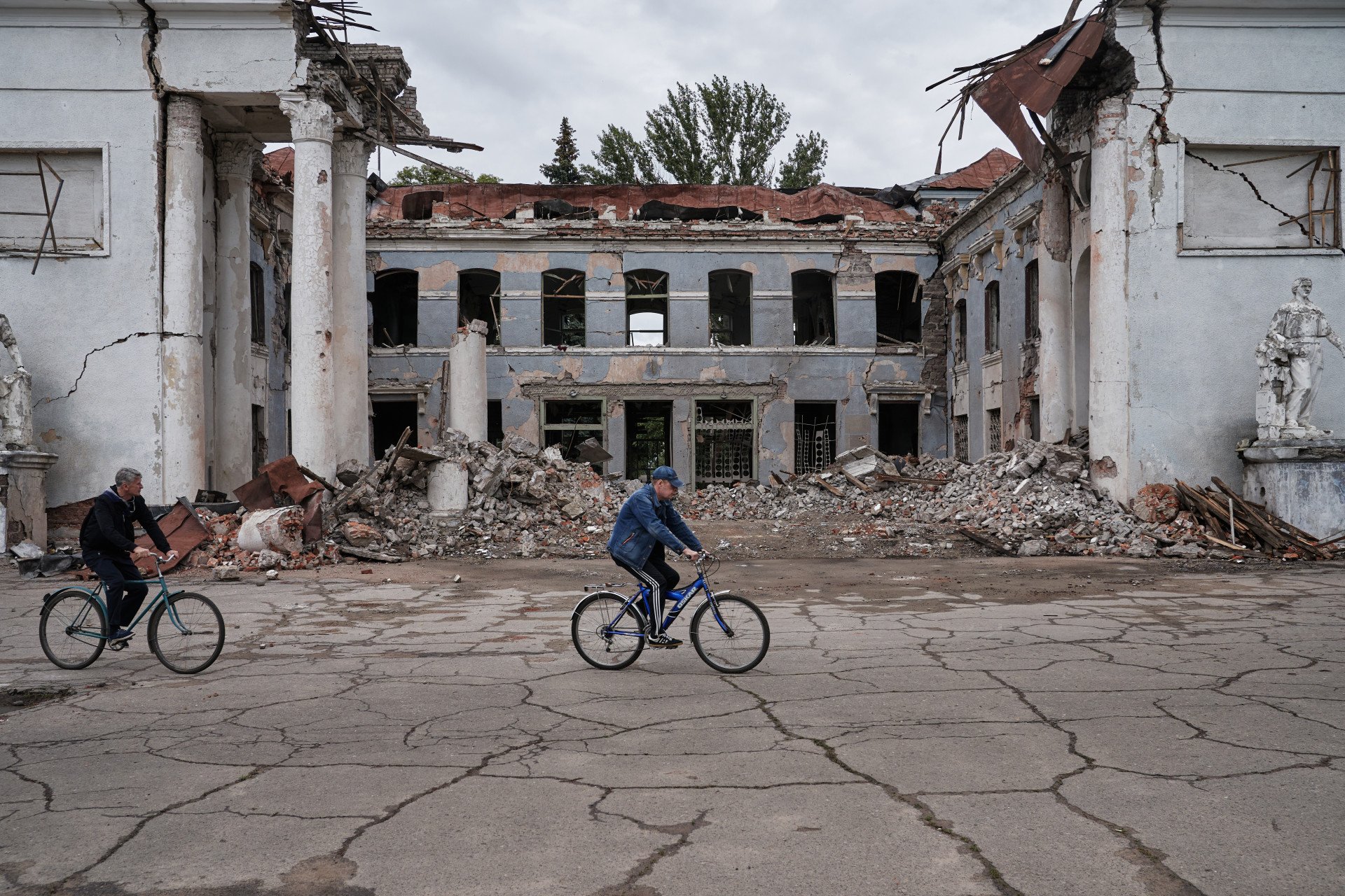 Locals of Kostiantynivka riding past a building hit by a Russian strike. Locals of Kostiantynivka riding past a building hit by a Russian strike.