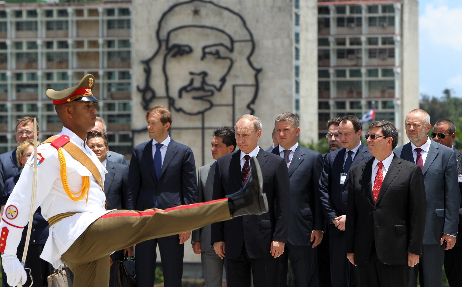 A Cuban honor guard marches as Russia’s leader stands with officials during a ceremony at Havana’s Revolution Square, with the iconic Che Guevara mural visible in the background