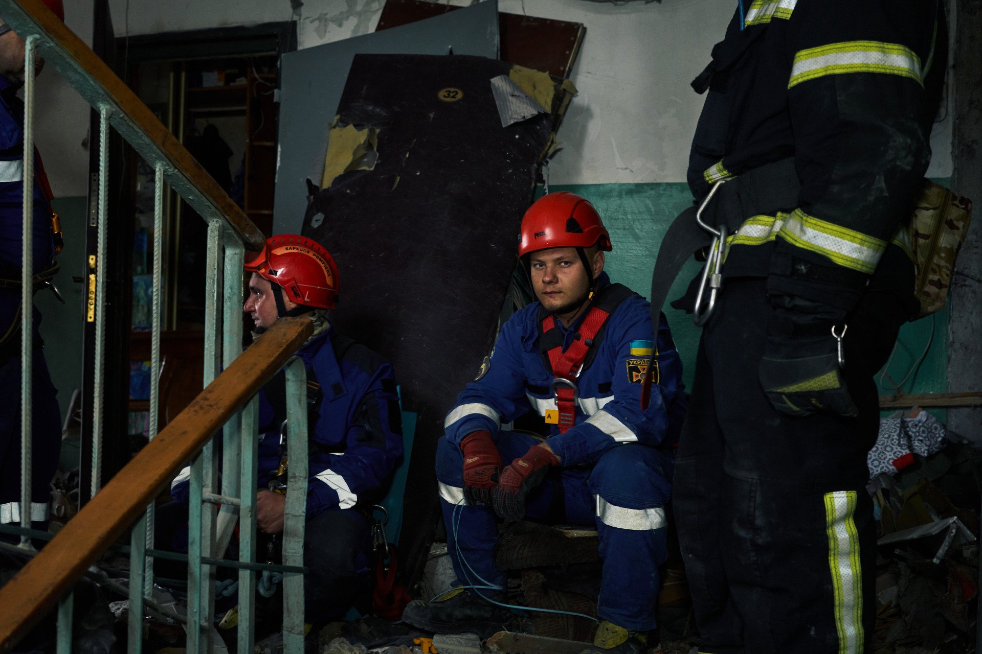 Exhausted Ukrainian rescuers pause inside a shattered stairwell during recovery efforts after Russia’s missile attack. Many had been working nonstop since the early morning strike. Kyiv, Ukraine. July 31, 2025. Photo by Josh Olley/UNITED24 Media