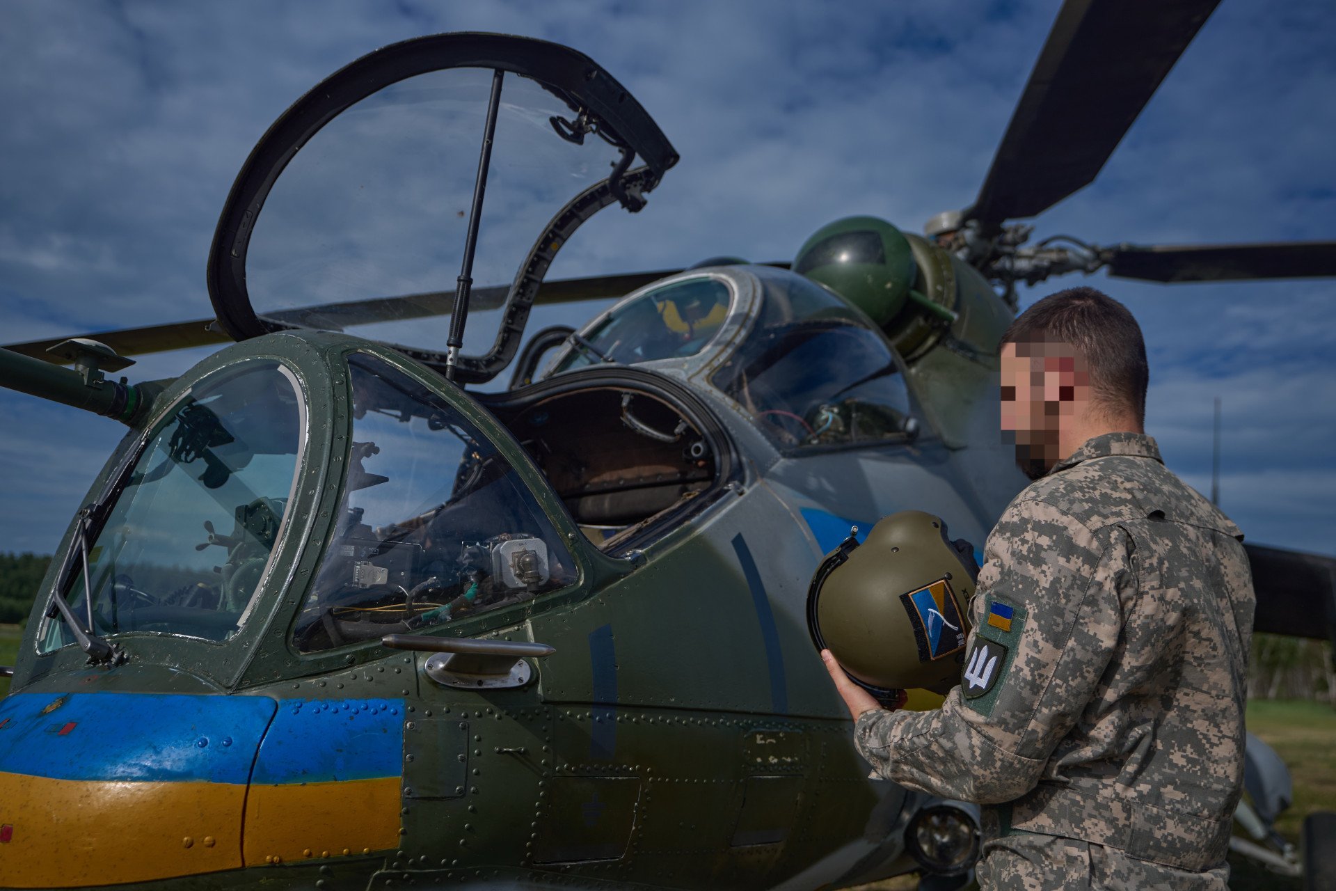 A Ukrainian Army aviator stands beside a Mi-24 helicopter, helmet in hand, moments before boarding. A Ukrainian Army aviator stands beside a Mi-24 helicopter, helmet in hand, moments before boarding.