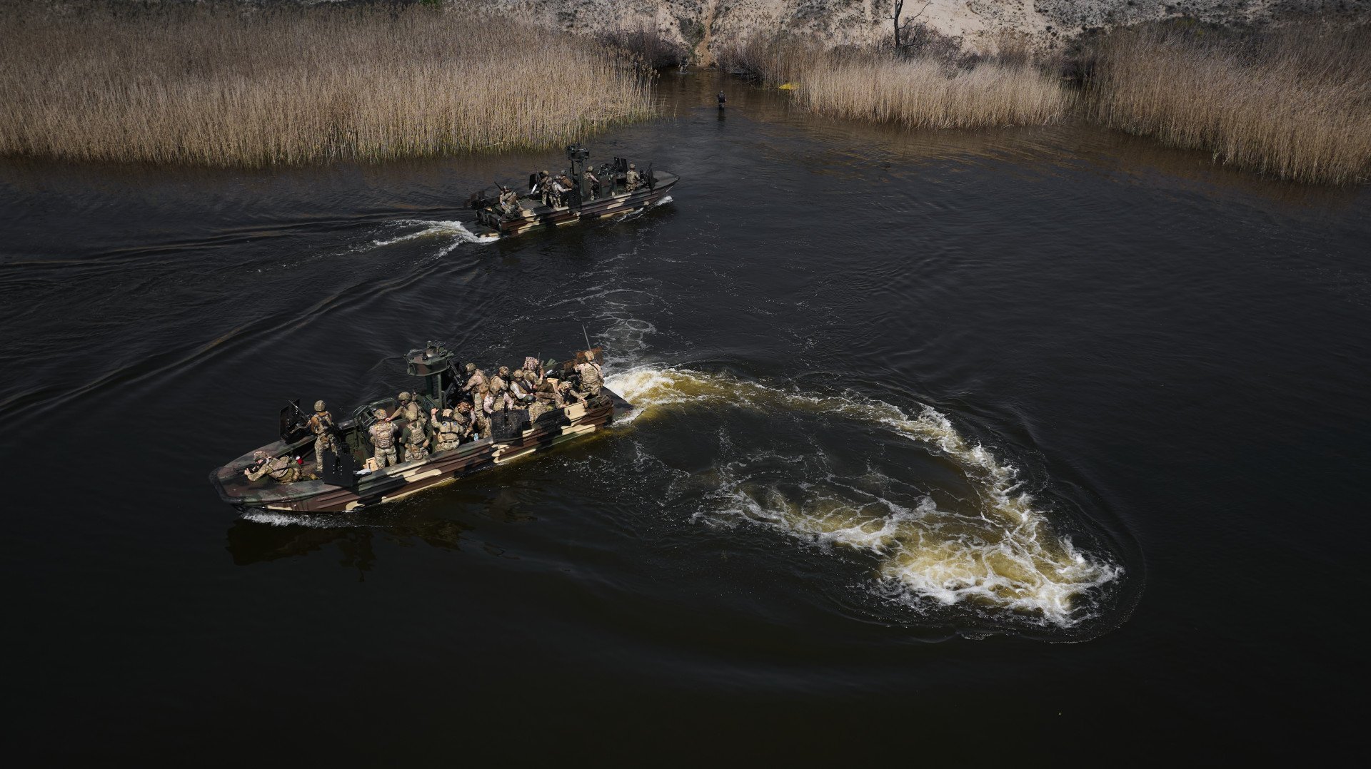 While one boat loads infantry troops, another maintains a safe distance, awaiting its turn to approach. While one boat loads infantry troops, another maintains a safe distance, awaiting its turn to approach.