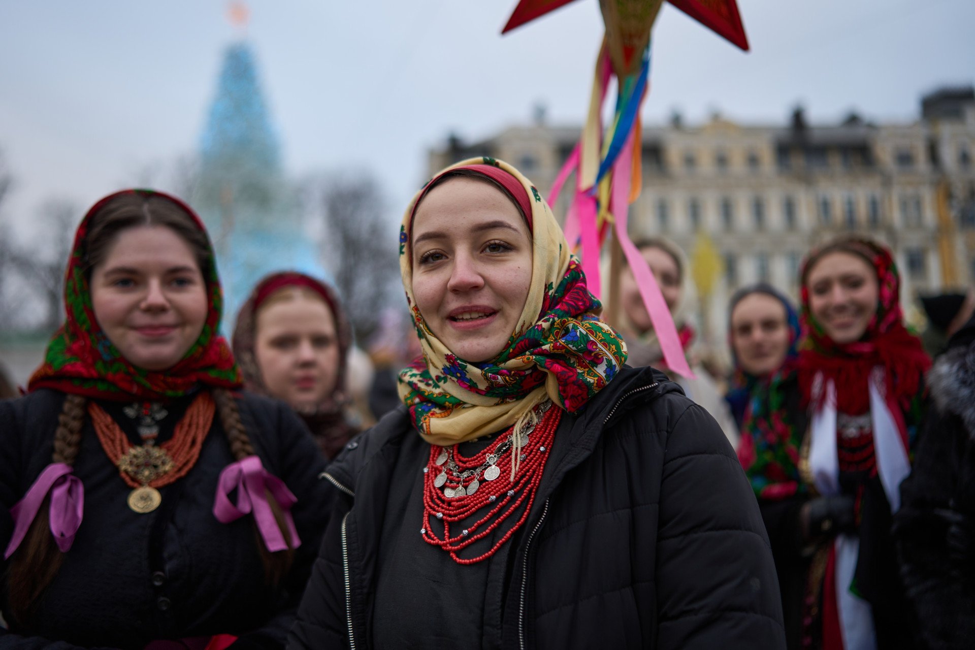 Participants wear embroidered shirts, headscarves, coral necklaces, and warm outerwear, highlighting the winter theme of the celebration.