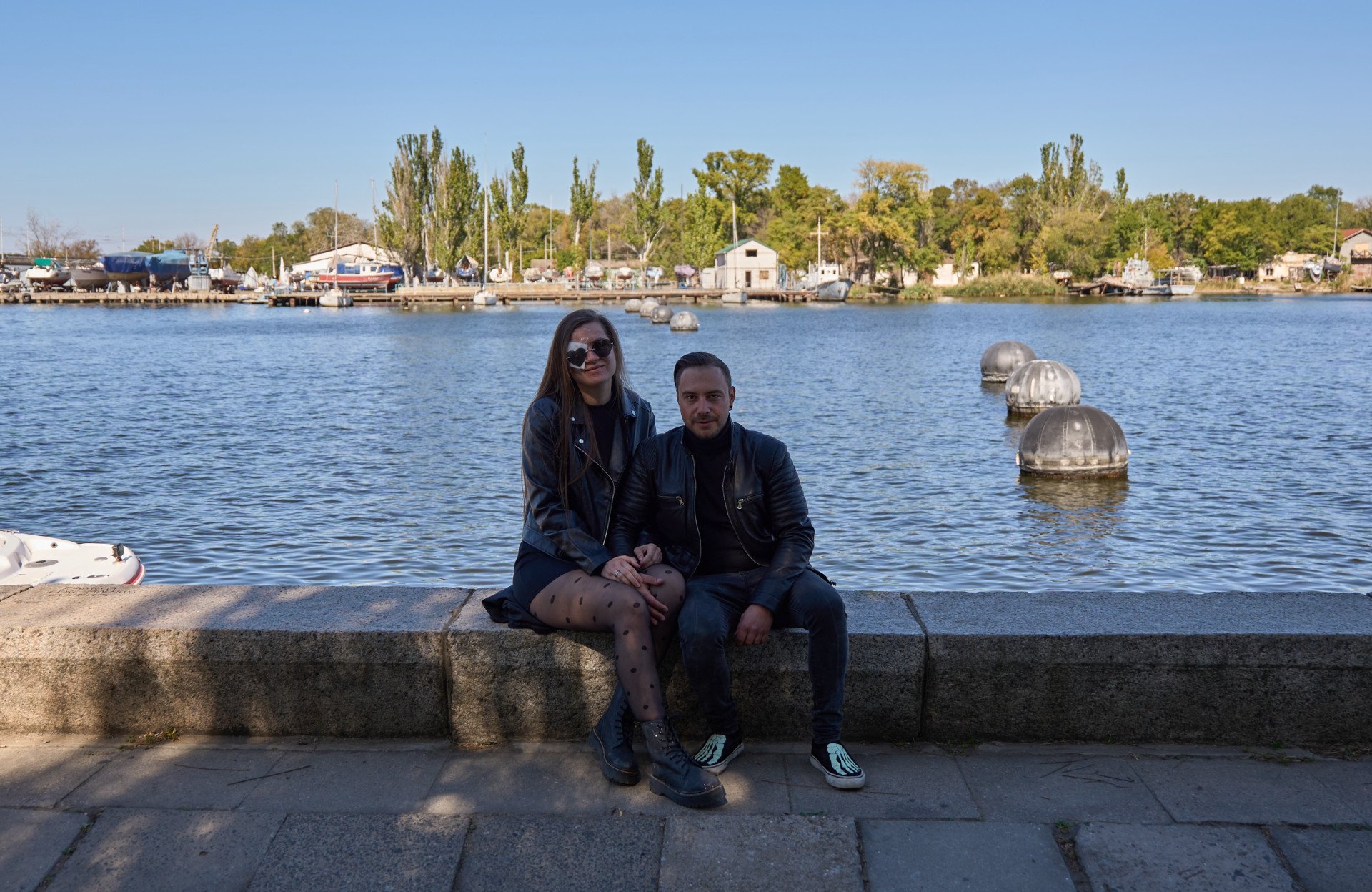 Yuliia and Valerii hold hands, sitting on the promenade along the Southern Buh river. Photo by Mykyta Shandyba / UNITED24 Media.