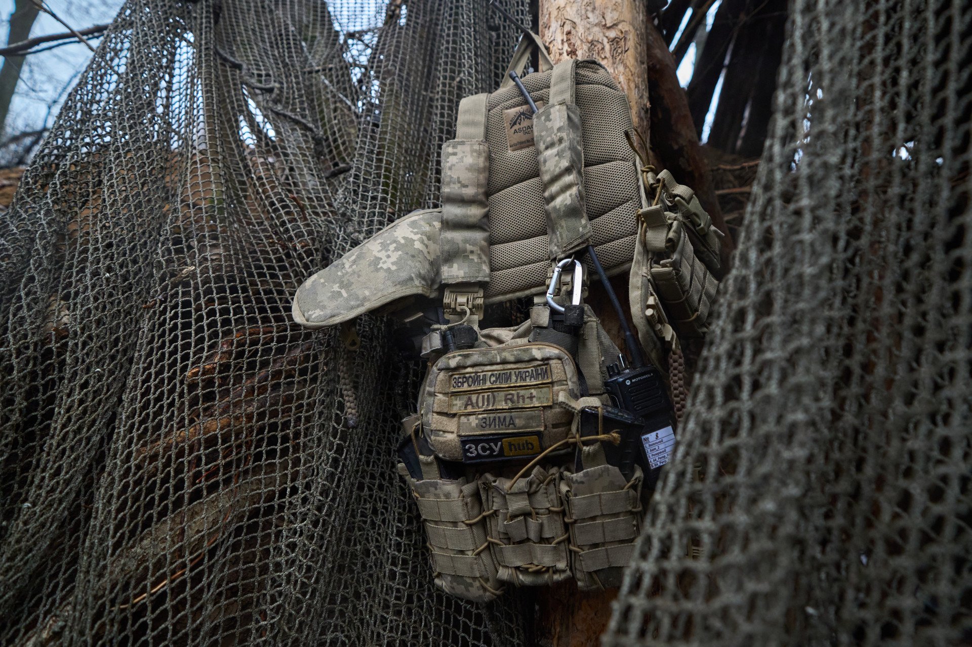 A bulletproof vest hangs on a nail near the entrance of the dugout protecting the howitzer. Among other patches, the blood type of the soldier, here A+, is a mandatory precaution and a stark reminder that life and death is only a matter of seconds in Ukrainian trenches.