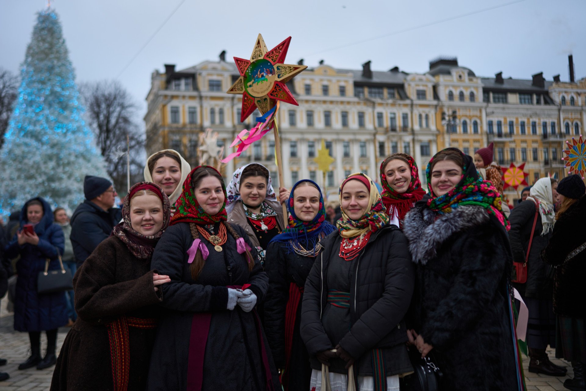 The people spread the festive mood and resilience in the city that has been living through war. Christmas tree is shining in the background.
