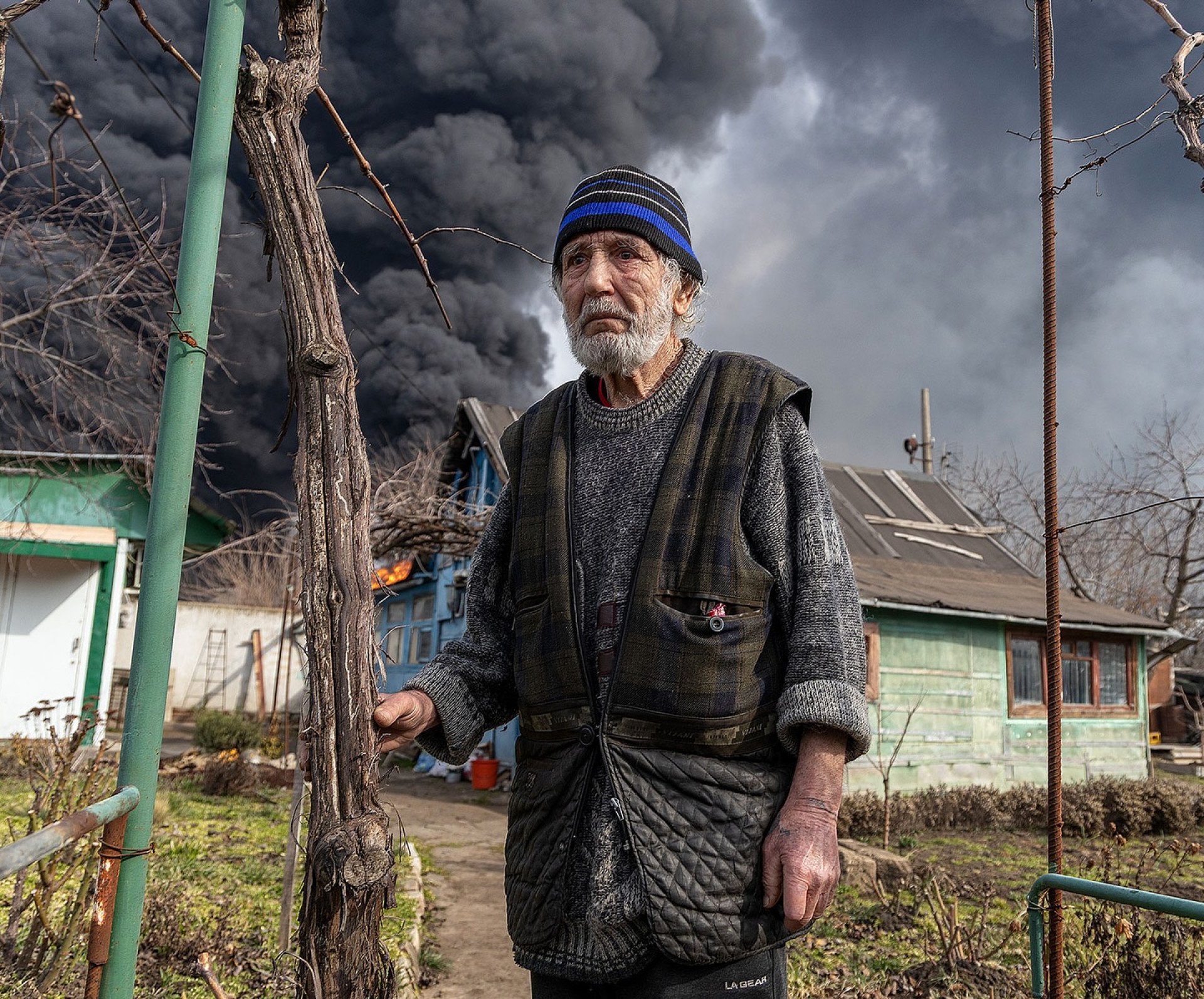 MAR 11 — Local resident in the aftermath of Russian attack on Odesa. Private homes and warehouses filled with toys lie in ruins. A fuel tank burns, sending thick black smoke over the city. (Photo by Oleksandr Gimanov @gimanov)