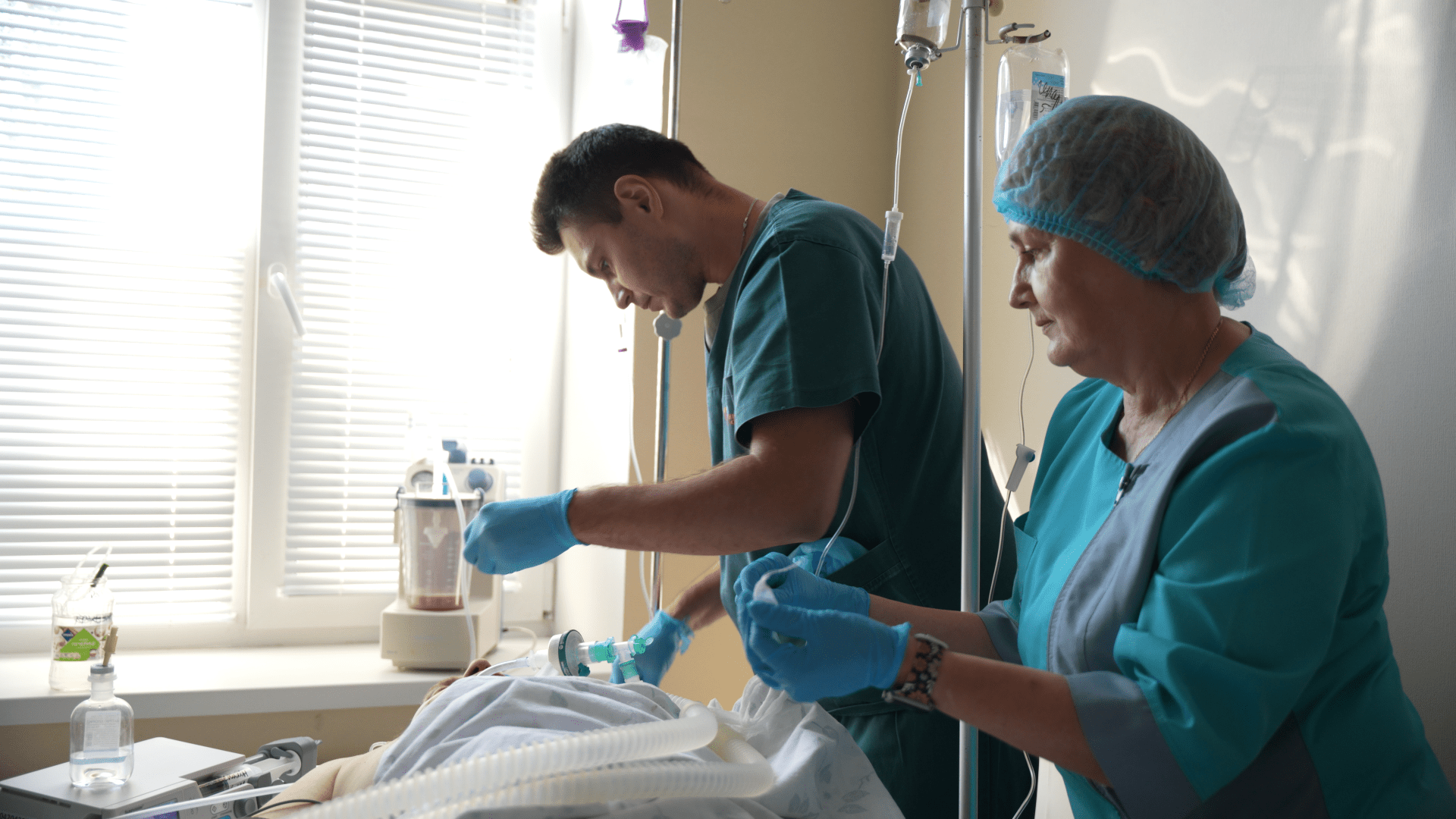 Inside a Kyiv intensive care unit, a surgeon and nurse carefully stabilize a brain-dead patient kept alive by mechanical life support. Every minute is vital as the team prepares the donor for the operating room, where his heart will be explanted and rushed into the chest of a waiting recipient—a complex, high-stakes relay that Ukrainian medical teams now routinely perform despite the unpredictable backdrop of wartime blackouts and air raids. (Photo: Mykyta Shandyba / UNITED24 Media) Medical team in a Kyiv hospital preparing a brain-dead donor patient on life support for an urgent heart transplant explant surgery.