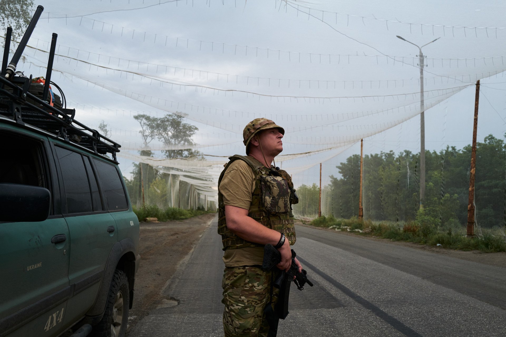 A Ukrainian soldier scans for Russian FPV attack drones on a road partially shielded by anti-drone netting in Kostyantynivka on August 11, 2025, where around 8,500 residents remain as fighting continues on the city’s outskirts. (Source: Getty Images)