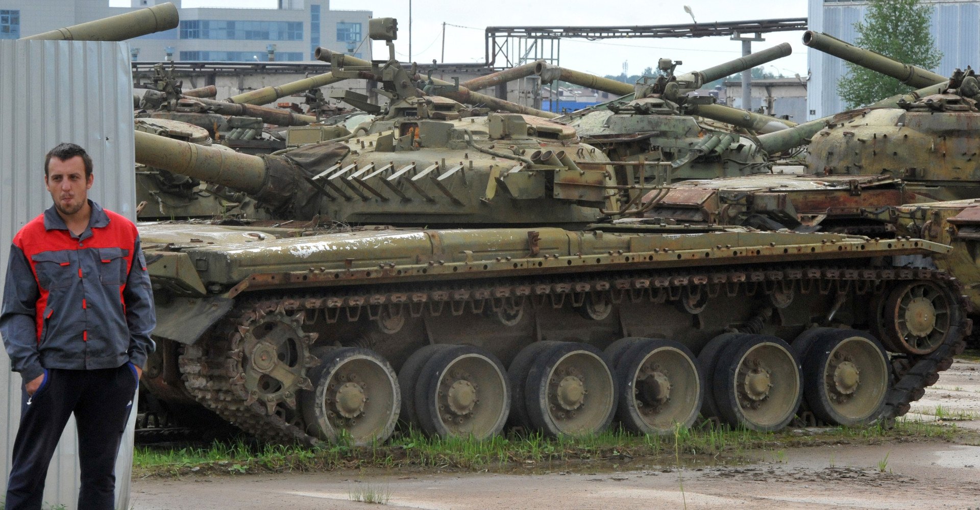 An employee looks at broken tanks parked during an open day at the Armored Vehicle repair plant in Strelna, outside Saint Petersburg, on August 5, 2016.