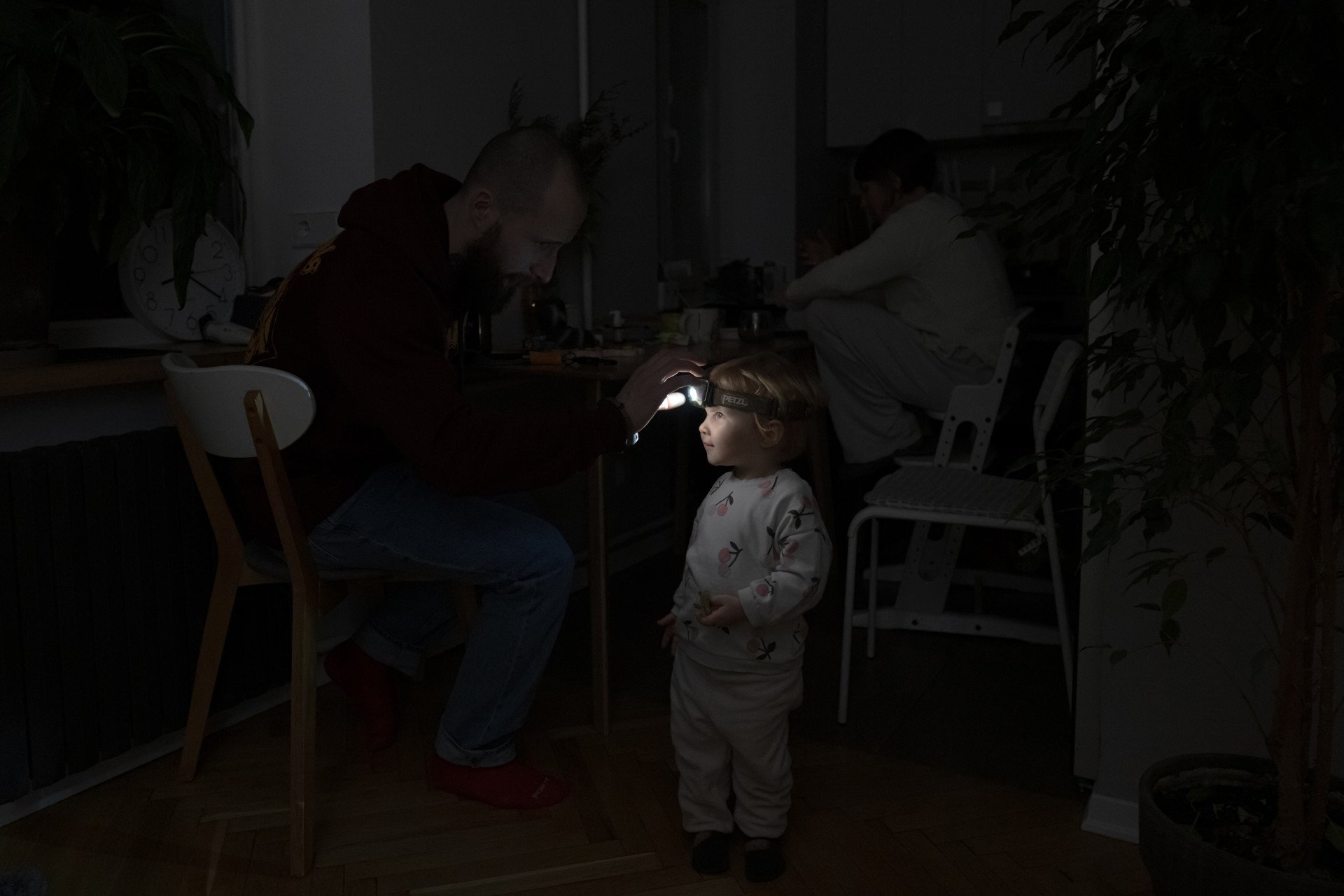 Local resident Stas helps his two-year-old daughter use a headlamp during a power outage in their Kyiv apartment on Jan. 13, 2026, amid Russia’s invasion of Ukraine. (Photo: Getty Images)