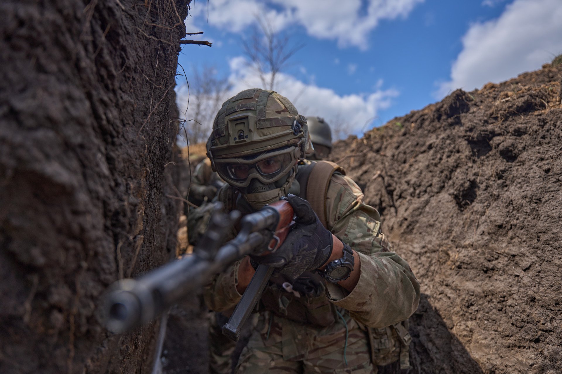 Un combatiente extranjero avanza por una trinchera con el fusil en alto, practicando movimientos rápidos y agresivos en condiciones de combate simuladas. Un combatiente extranjero avanza por una trinchera con el fusil en alto, practicando movimientos rápidos y agresivos en condiciones de combate simuladas.