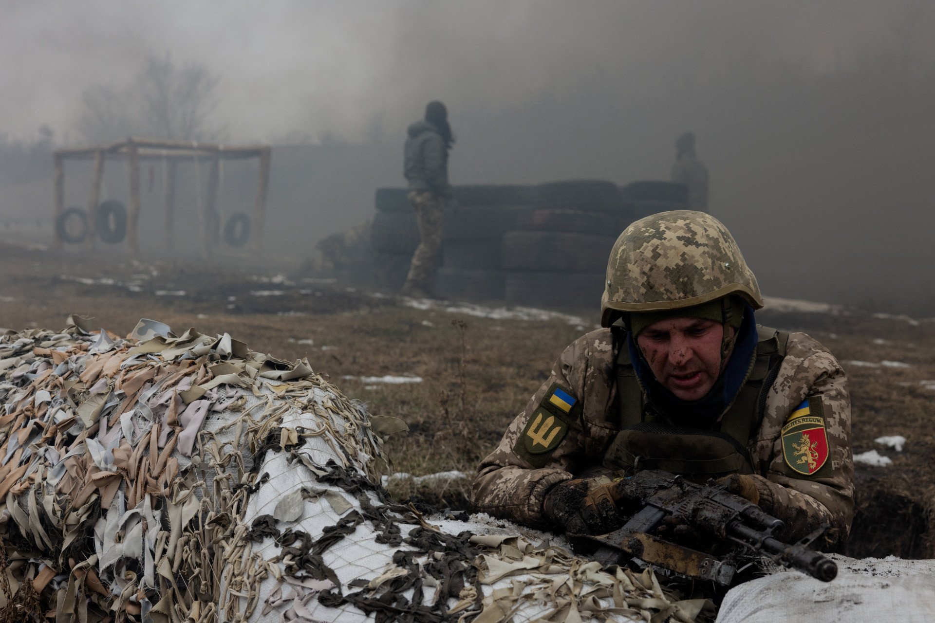 A serviceman in the 24th Mechanized Brigade takes position behind sandbags covered with camouflage netting during a training drill in eastern Ukraine on March 4, 2025. (Photo by Tetiana Dzhafarova/AFP via Getty Images)