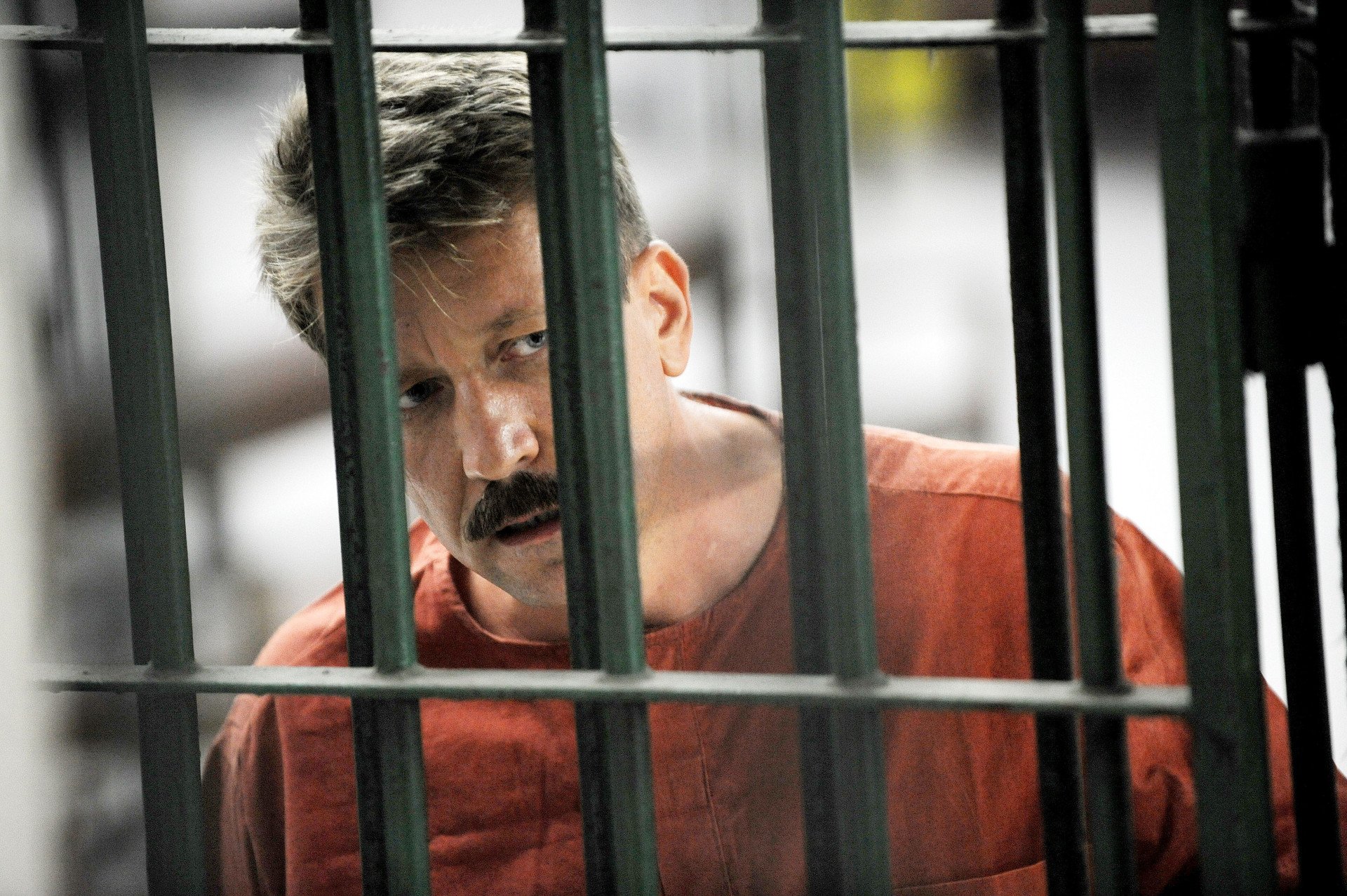 Alleged Russian arms dealer Viktor Bout looks on as he stands behind bars