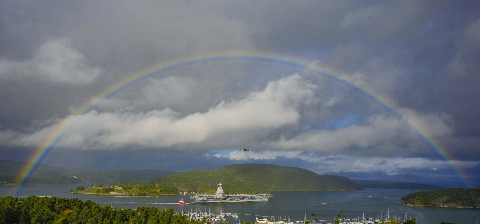 A rainbow spans over the US aircraft carrier USS Gerald R. Ford that is on its way into the Oslofjord, here at Drøbak and Oscarsborg, on September 12, 2025