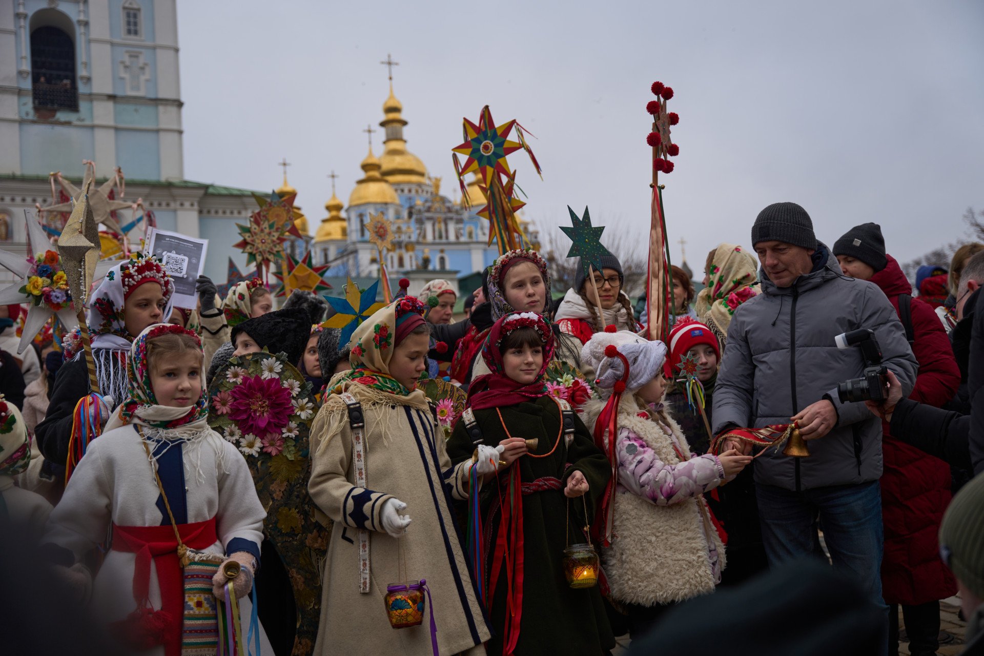 The vibrant crowd fills Sophia Square, while the domes of St. Michael’s Golden-Domed Monastery glow in the background.