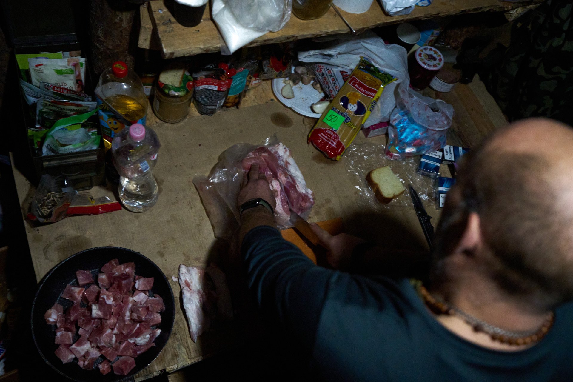“What are you cooking?” “It’s bolognese today,” smiles Ruslan, cutting through a big block of meat. The improvised kitchen, hidden in a dugout, is well-equipped with spices and a small fridge, allowing them to eat something other than the usual military rations. Between two hits on the Russians, cooking hearty meals provides a warm interlude for those soldiers who have been fighting for almost three years.