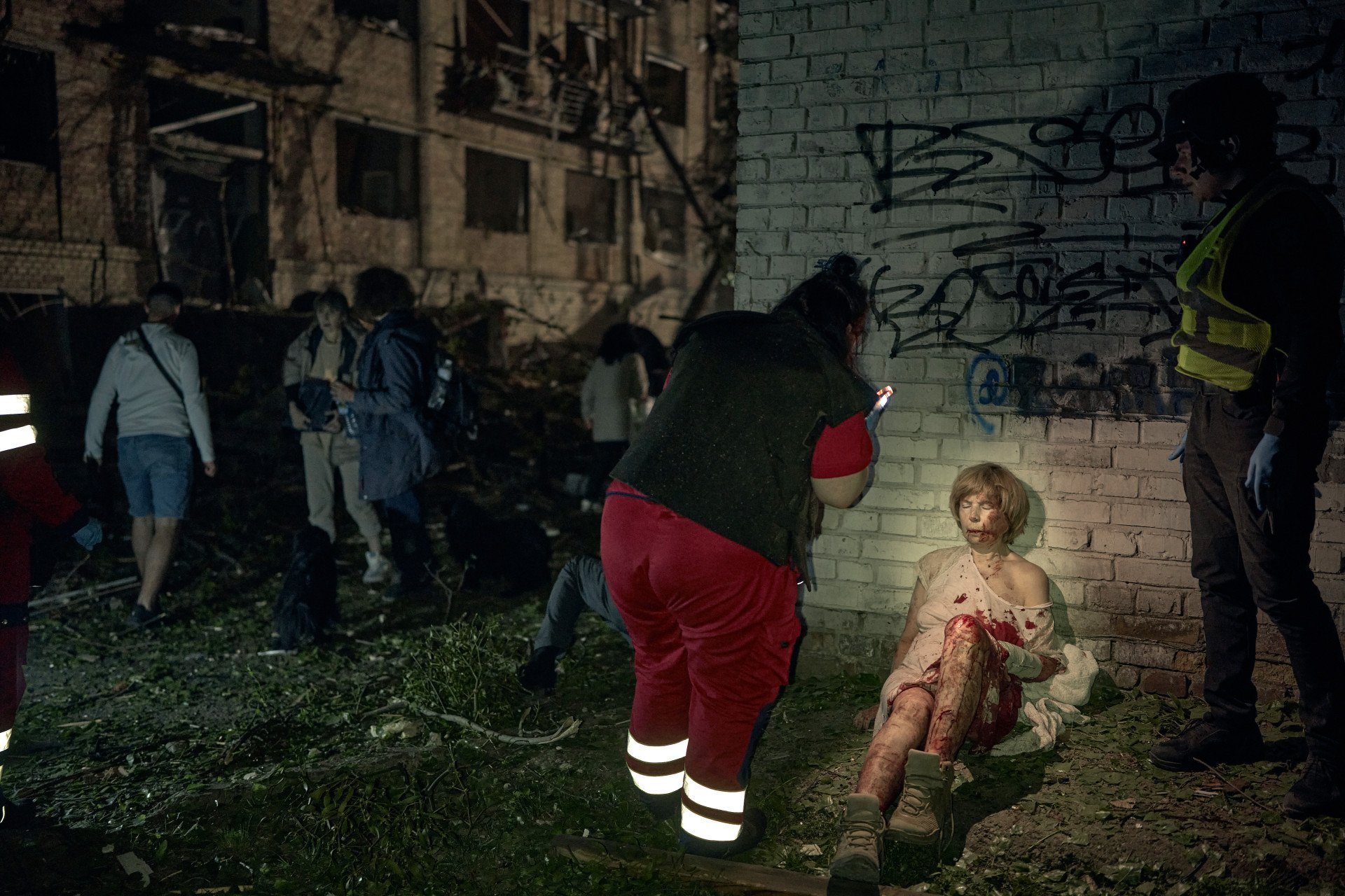 An injured woman wears a pair of military boots given to her by a stranger to protect her bare feet after the missile strike. Rescuers and civilians work through the night to pull victims from the wreckage after a missile reduced a Kyiv apartment building to ruins on April 24, 2025. Among the 90 injured: six children and a pregnant woman. (Photo: Kostiantyn Liberov/Libkos/Getty Images)