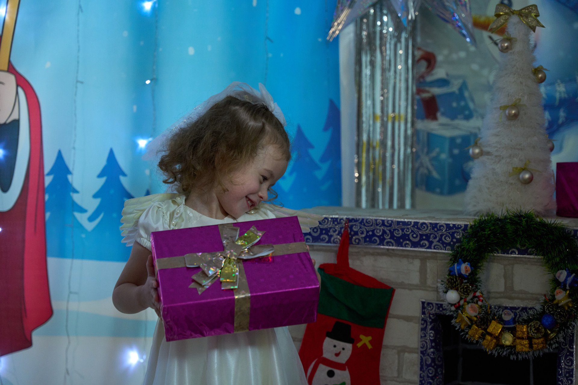 A girl smiles while holding a wrapped gift box during the celebration of St. Nicholas Day at one of Zaporizhzhia’s underground kindergartens, Zaporizhzhia region, Ukraine, December 2025. Photo by Mykyta Shandyba / UNITED24 Media.