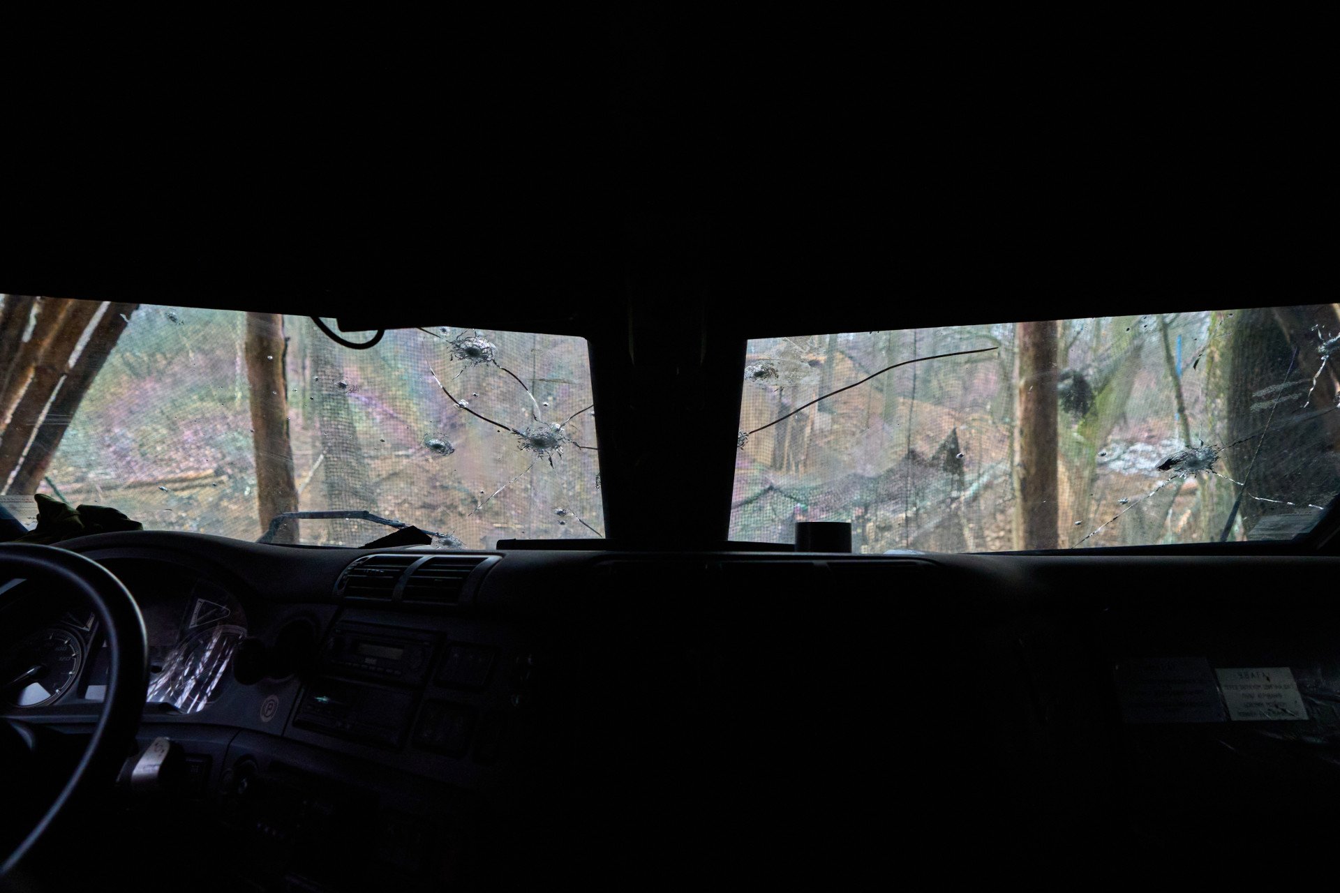 A view from inside the cabin of the howitzer, hidden in a dugout and waiting for action. The windshield is riddled with bullet impacts. Yet, the armored cabin is thick enough to sustain a few hits and protect the driver from a hail of bullets if the Bohdana is under fire. 