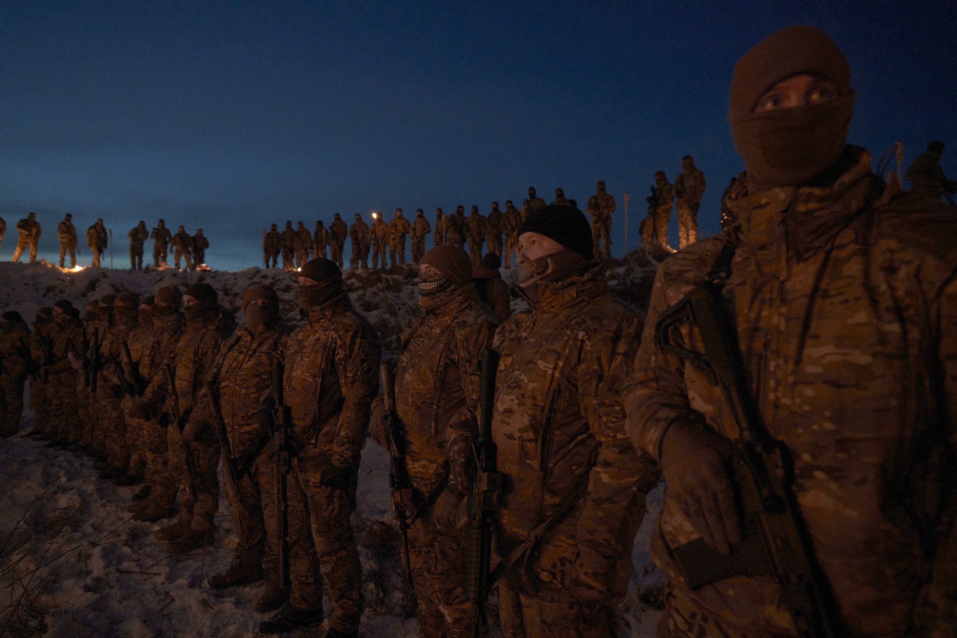 Members of the ceremony, masked in balaclavas and carrying rifles, watch as the ceremony begins. March 2026. Photo by Joshua Olley/UNITED24 Media.
